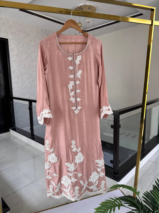 Pink dress with white lace details on a hanger in a room.